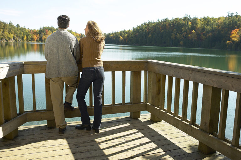 Couple relaxing on deck of their lakefront vacation home.