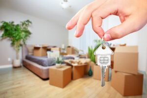 Home seller holding keys in front of packed home—moving in a seller's market concept