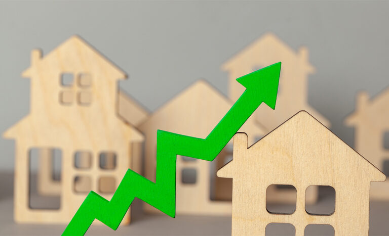 Wooden houses with arrow chart rising to represent market inflation