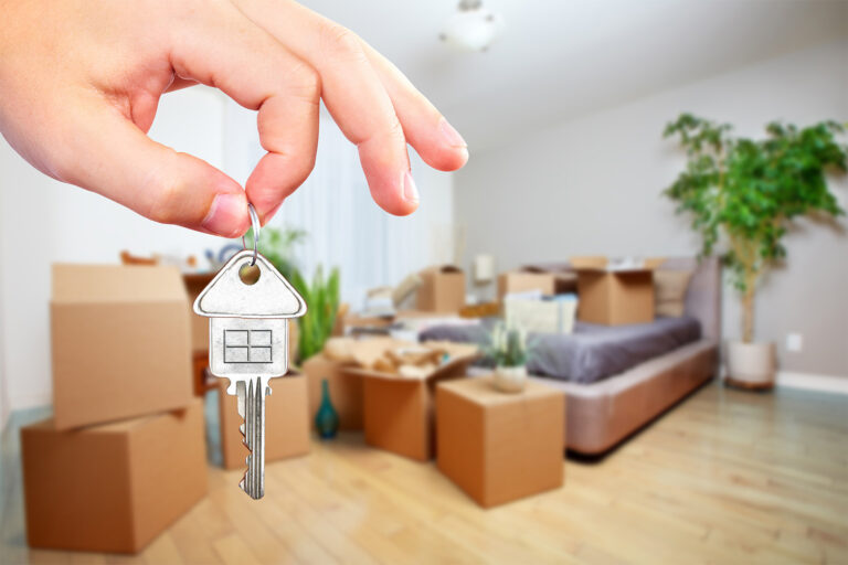 Home selling concept with house key and packed boxes.