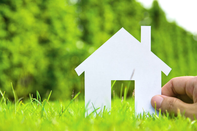 Paper house in a field, representing home inspection process