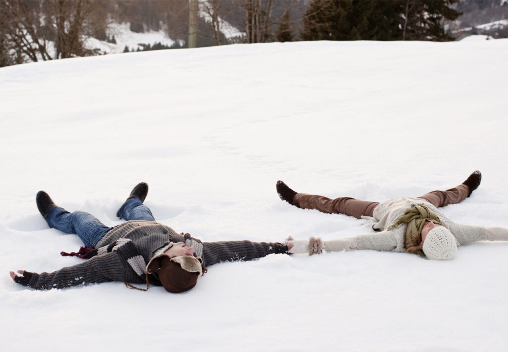 Happy couple making snow angels - winter move concept