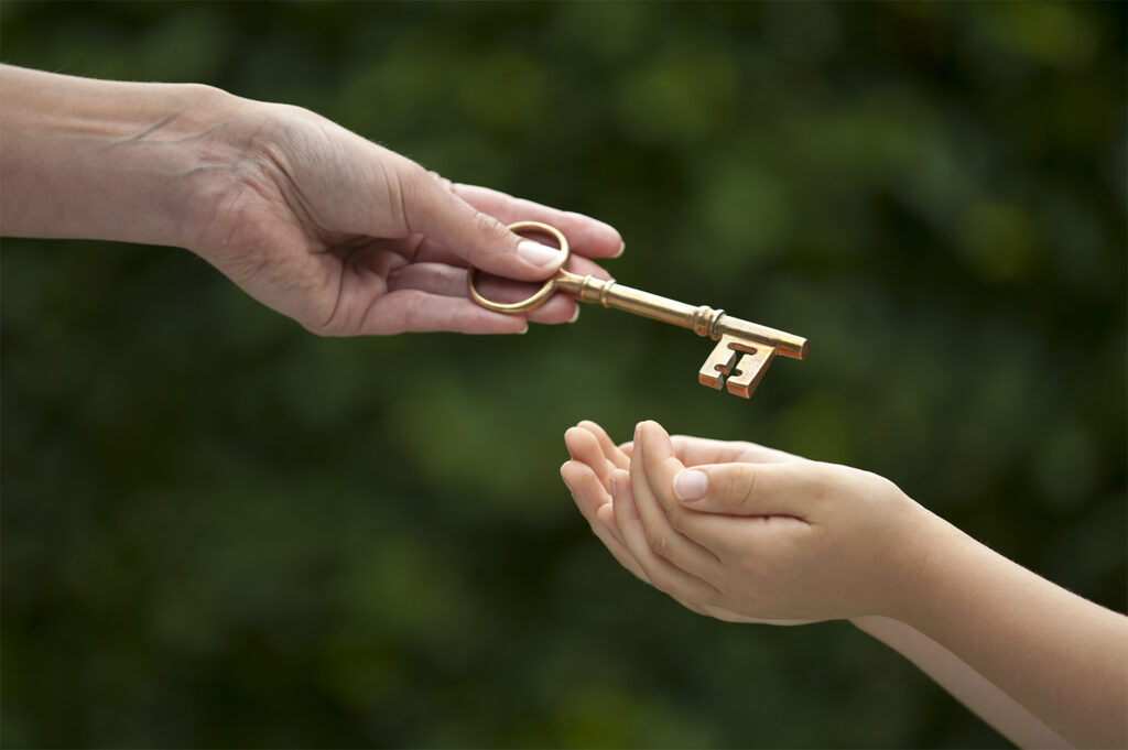 Parent handing key to child, representing selling a family home or inheritance