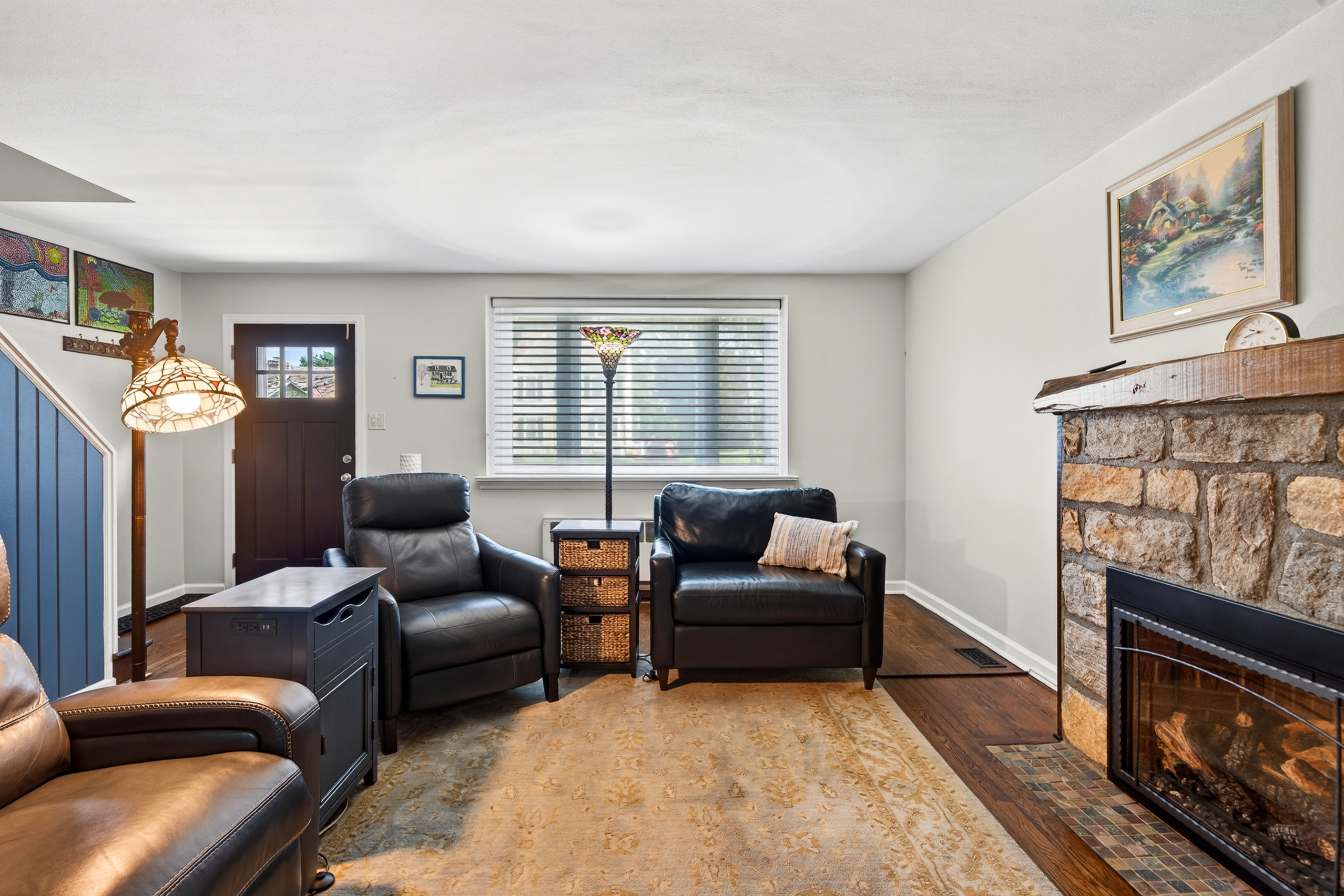 Living room with stone-surround gas fireplace and antique wood mantle