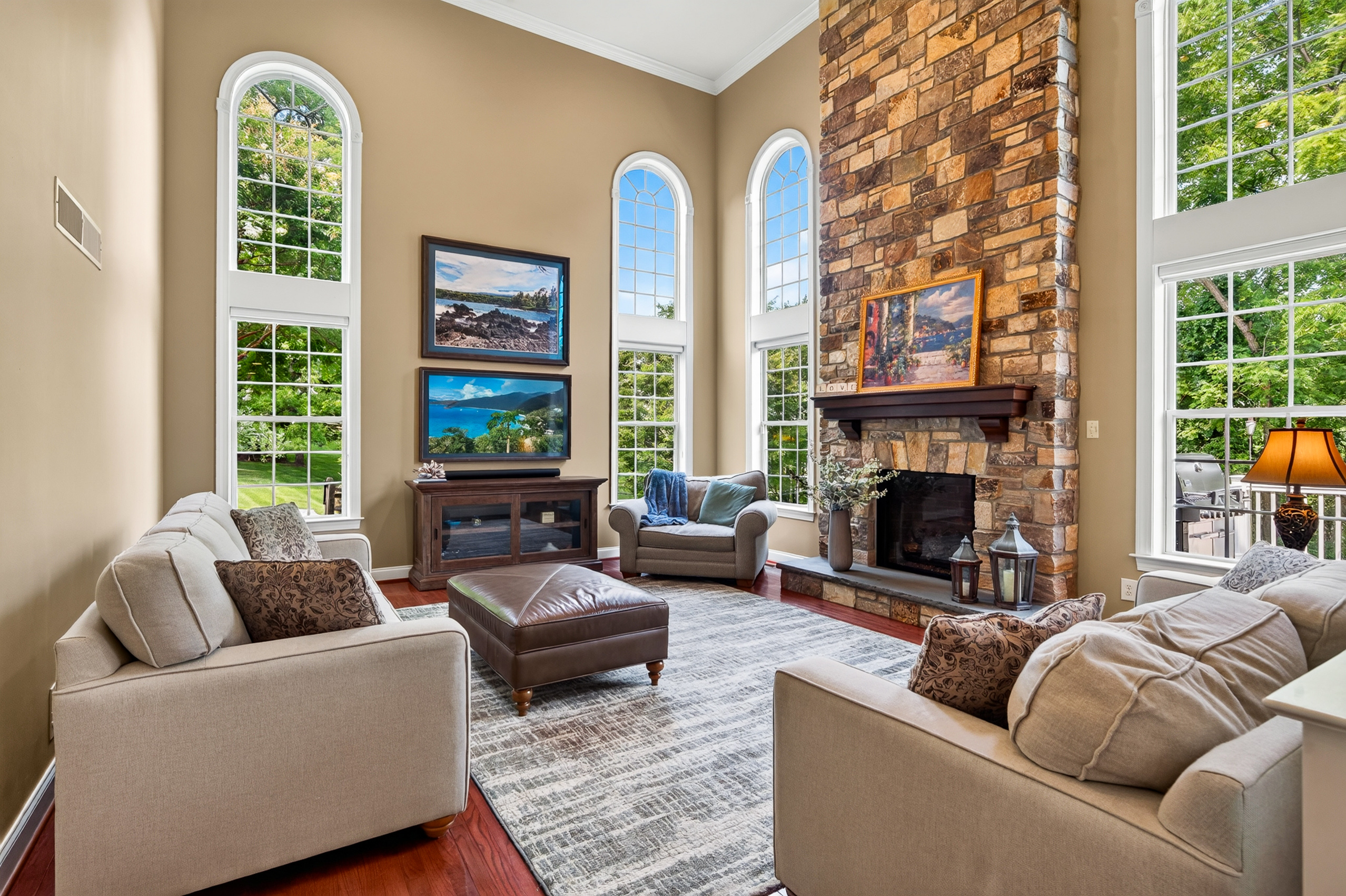 Two-story family room with floor-to-ceiling stone fireplace and arched windows