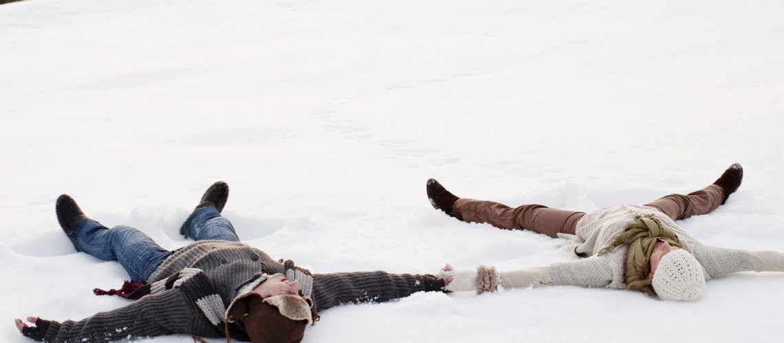 Happy couple making snow angels - winter move concept
