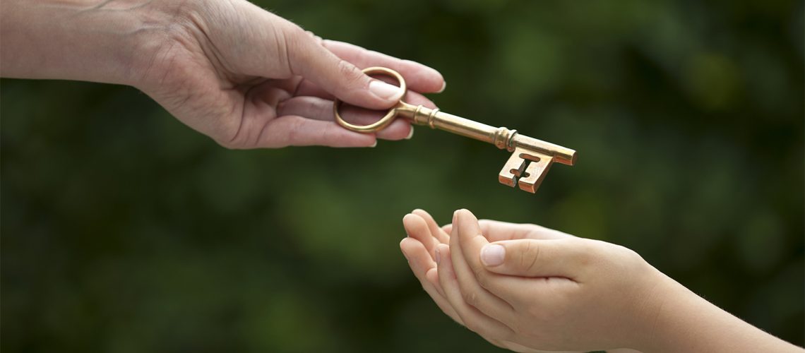 Parent handing key to child, representing selling a family home or inheritance